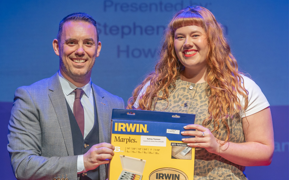 Student prizewinner with college principal Simon, holding prize of tools