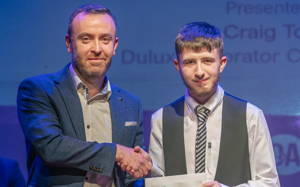 Prizegiving sponsor shaking students hand while they hold prize envelope