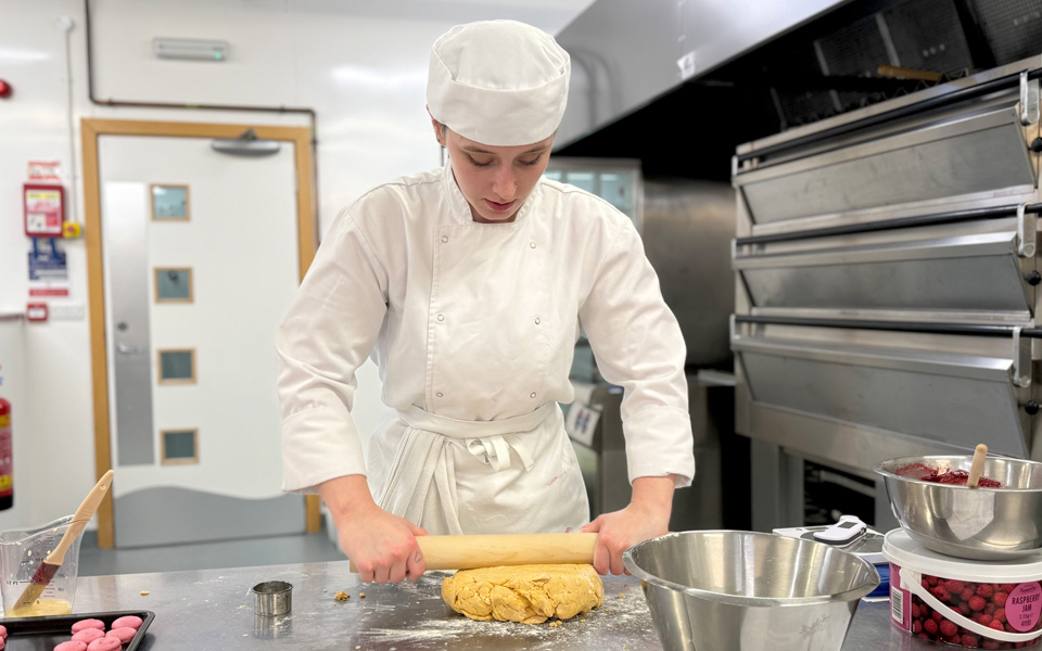 Student rolling dough out in kitchen