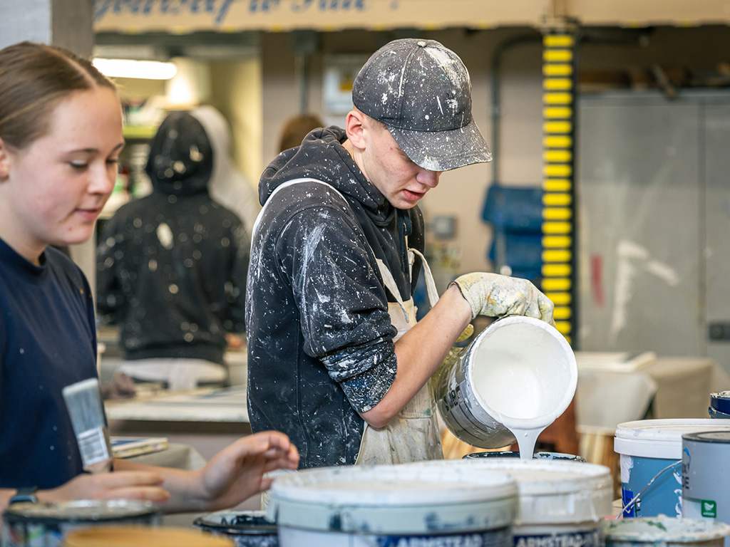 Student pouring paint into roller tray