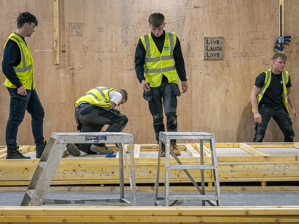 Four joinery students building a wood structure