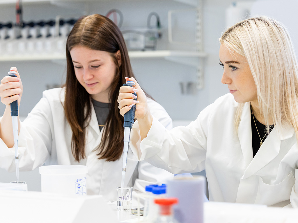 Students in lab-coats using a dropper
