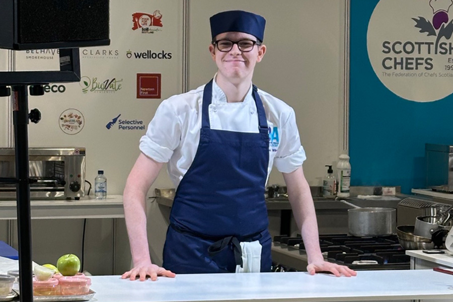 Cookery student smiling at camera at cooking competition workbench