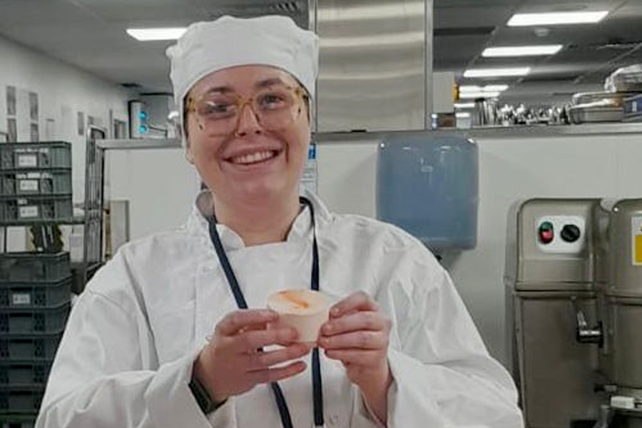 Student in chef whites smiling at camera 