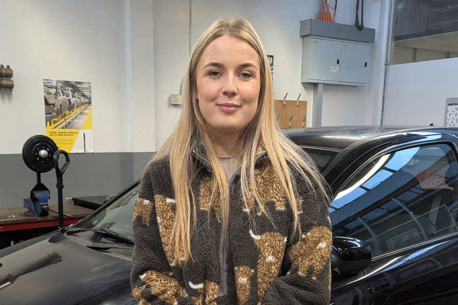 Motor Vehicle student in garage standing in front of car