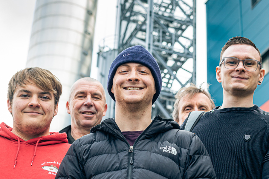 Group of engineering students smiling in front of pylon