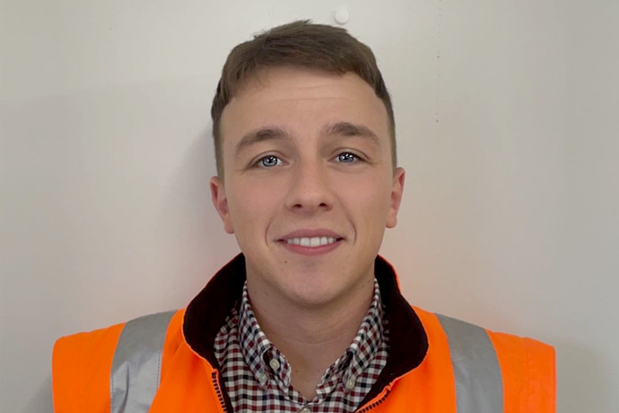 Student smiling at camera wearing orange high vis vest