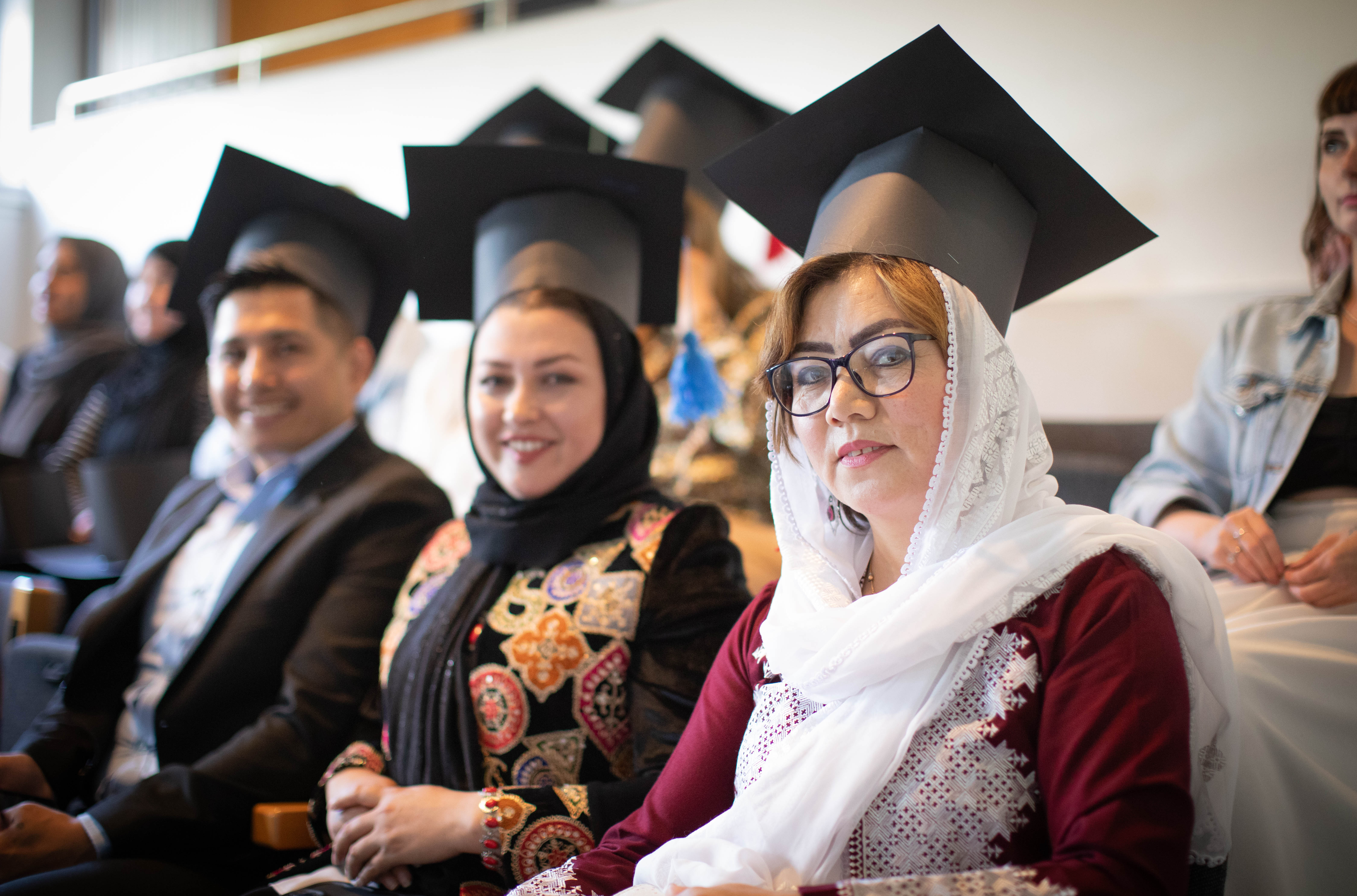 ESOL students sitting wearing graduation caps that they made from cardboard)